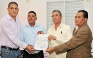 El director del Fondo de Desarrollo Agropecuario (FEDA), Antonio López y Justo Guzmán, coordinador de los proyectos presidenciales entregan el cheque del préstamo